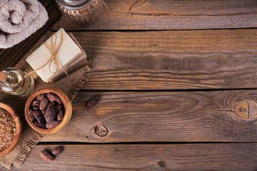 Natural cosmetic oil, sea salt and natural handmade soap with cocoa beans on rustic wooden background
