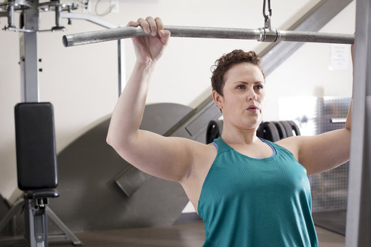 Curvy woman exercising on machine in gym