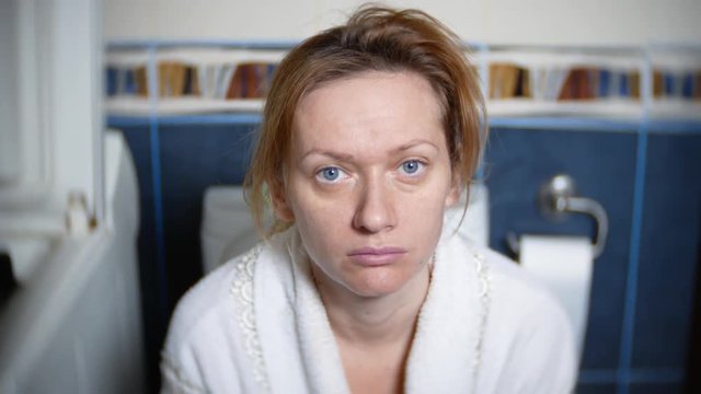 portrait. pale woman is sitting in the toilet on the toilet. 4k, blurred background.