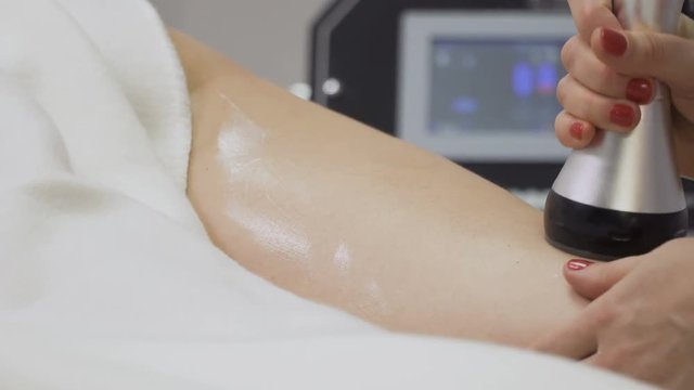 Beautician massages woman's leg and makes rf-lifting procedure