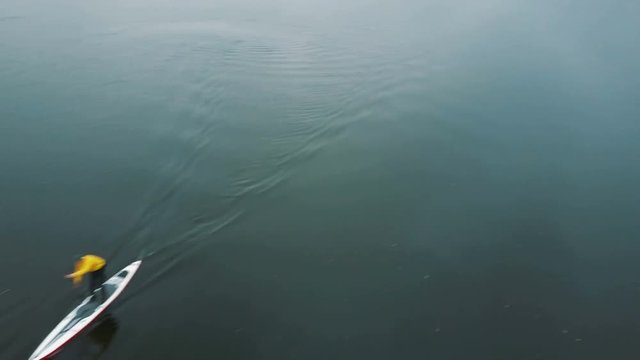 Closeup of a professional rower demonstrating stand up paddling techniques. Sup board aerial drone footage.