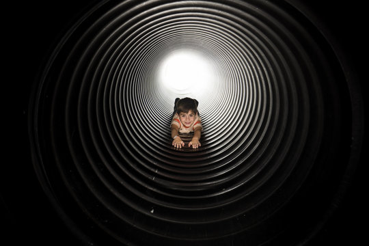 Portrait of playful boy lying in huge metallic pipe