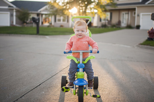 Portrait of baby boy riding tricycle on road
