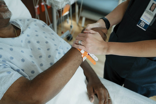 Close up of nurse comforting senior patient in hospital ward