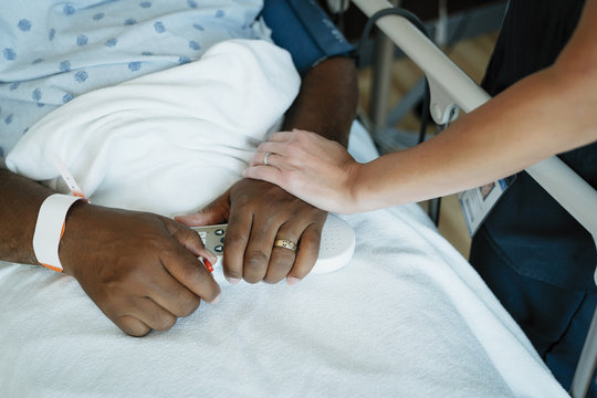 Close Up Of Nurse Comforting Senior Patient In Hospital Ward