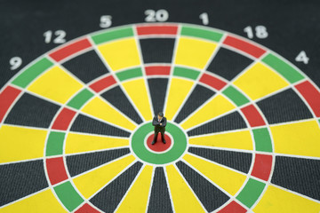 MIniature toy.Business man stand on dart board thinking about target of...