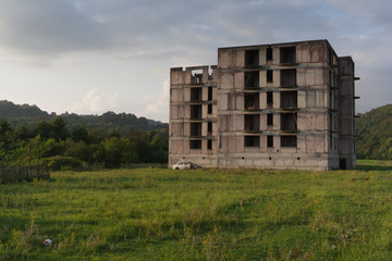 Unfinished abandoned concrete building at green field
