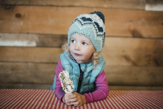Cute girl looking away while holding ice cream at table