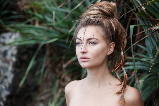Portrait of young pretty woman with naked shoulders and feathers in hair