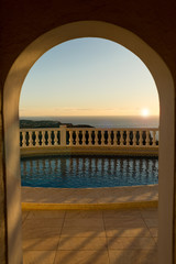 View of the swimming pool through the arch at sunset.