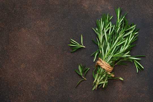 A fresh bunch of rosemary on a brown concrete background. Organic food background.