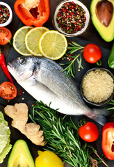 Food background. Fresh, raw Dorado with a swallow, lemon, avocado on a dark concrete background.