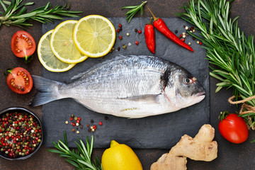 Food background. Fresh, raw Dorado with a swallow, lemon, avocado on a dark concrete background.