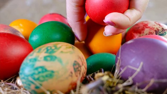 Female hand puts eggs on a pile of easter eggs in straw, 4k