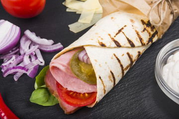 Burito with ham, tomatoes and jalapeno pepper.