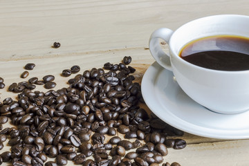 Black coffee with coffee beans on wooden background