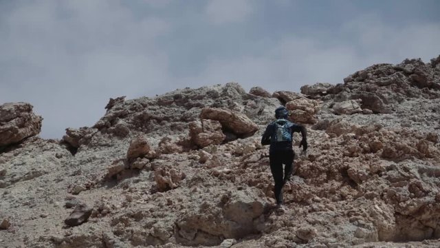 Aerial view of a man running down of a volcano peak. Slow motion