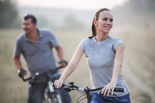 Happy young couple with bicycles in countryside.