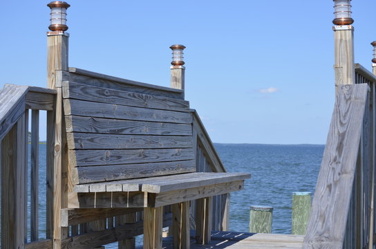 Tall backed bench on a walkway leading the waterfront and beach