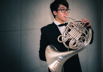 Musicain playing instrument horn in the hall - obrazy, fototapety, plakaty