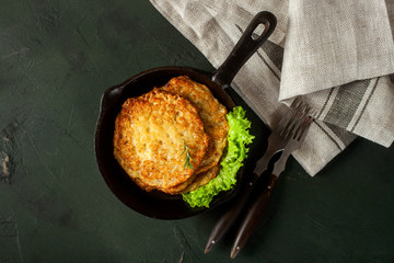 Potato hash brown with salad on a dark background. Latkes. The Jewish dish for a holiday Hanukkah. Top view - obrazy, fototapety, plakaty