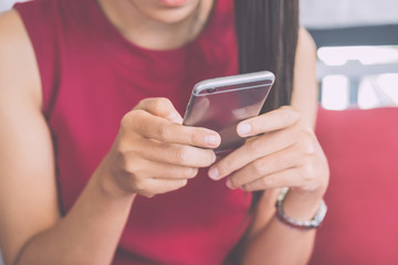 Hand of woman using smartphone on wooden table.