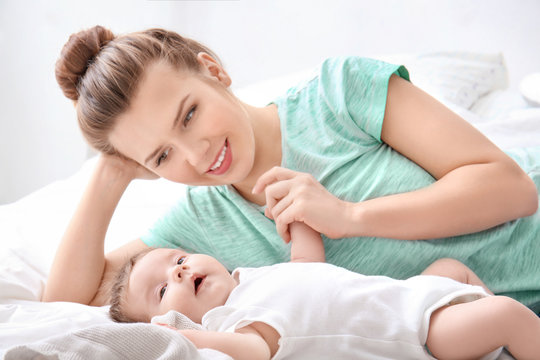 Young mother and cute baby on bed at home