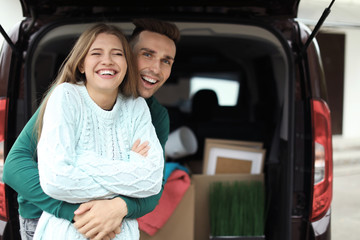 Young couple having break near their car on moving day