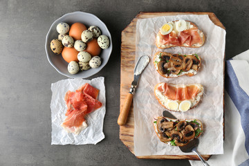Composition with tasty toasts, quail eggs, mushrooms and bacon on table