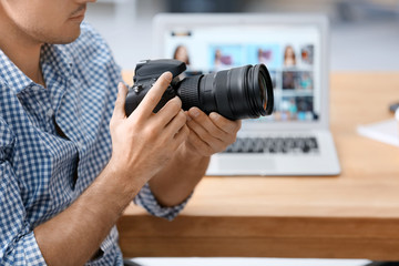 Young professional photographer with camera in office