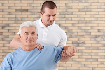 Physiotherapist working with patient on brick wall background