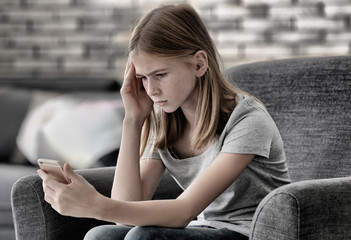 Sad teenage girl with smartphone at home © Africa Studio