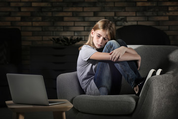 Fototapeta na wymiar Sad teenage girl sitting near laptop in dark room