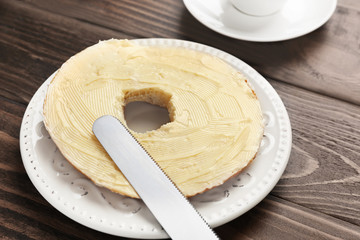 Tasty cut bun with butter on wooden table