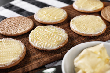 Tasty cookies with butter on wooden board, closeup
