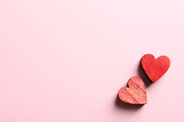 Two wooden hearts on color background