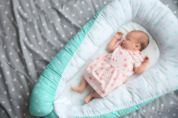 Cute newborn baby girl lying on bed
