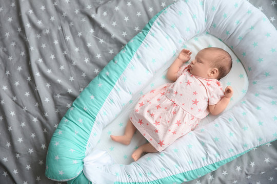 Cute newborn baby girl lying on bed