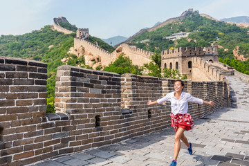 Happy cheerful joyful tourist woman at Great Wall of china having fun on travel smiling laughing and dancing during vacation trip in Asia. Girl visiting and sightseeing Chinese destination in Badaling