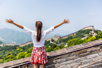 Happy cheerful tourist woman at Great Wall of china having fun un arms outstretched on travel during vacation trip in Asia. Girl visiting and sightseeing Chinese destination in Badaling