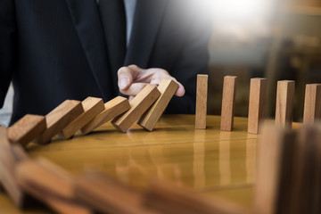 businessman hand stop dominoes continuous toppled or risk with copyspace.