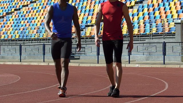 Self-confident athletes walking to locker room after grueling workout, slow-mo