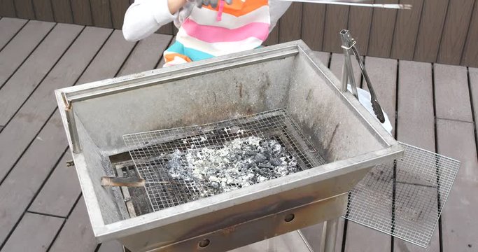 Woman cleaning barbecue stove at outdoor