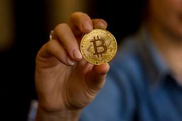 Naklejka na ściany i meble Woman holding a golden bitcoin physical coin