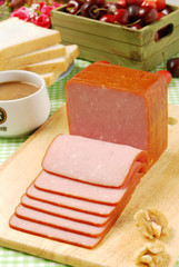 Slices of ham on a wooden board.    