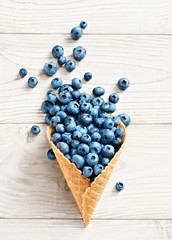 Blueberry explosion. Photo of blueberry in waffle cone on white wooden table. Top view. High resolution product.