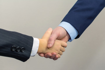 Success concept in business - handshake of man and kid.