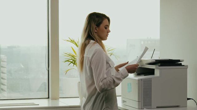 young businesswoman prints on the printer in the office