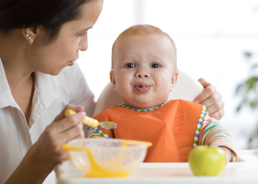 Mom feeds her kid. Baby is crying, capricious and refusing to eat