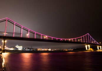 Multicolored bridge over the river at night